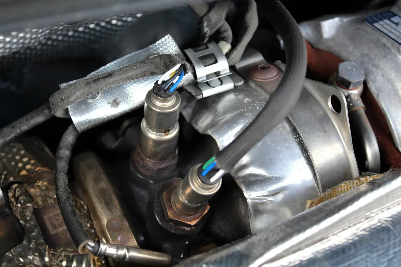 Sonde lambda défectueuse : câblage visible, connecteurs et partie métallique rouillée. Un symptôme de problème moteur.