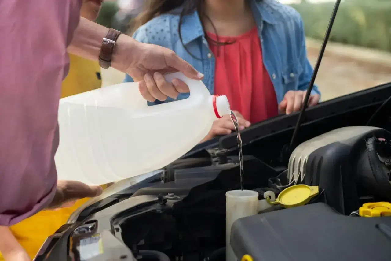 Main d'homme versant du liquide dans le réservoir, vérifiant le niveau liquide de frein.