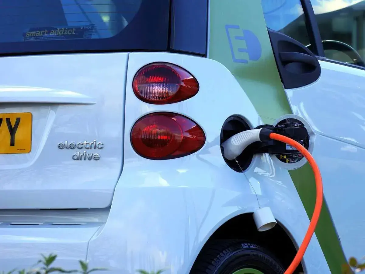 Une voiture électrique blanche est branchée. La question est : peut-on laisser charger une batterie de voiture toute la nuit ?