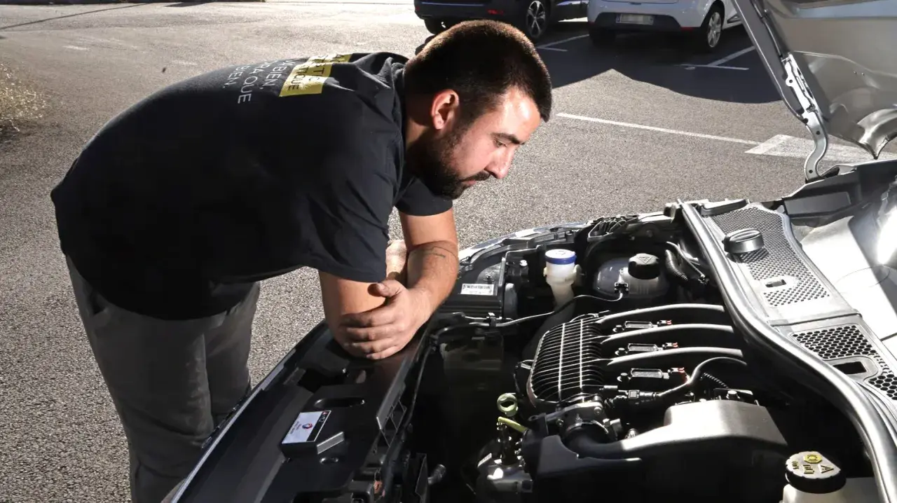 Un mécanicien examine un moteur de voiture, soucieux du risque de casse moteur.