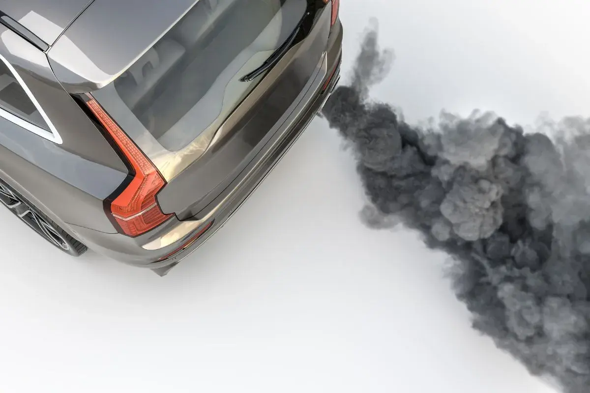 Vue aérienne d'un SUV gris émettant une épaisse fumée noire d'échappement, symbolisant la pollution.