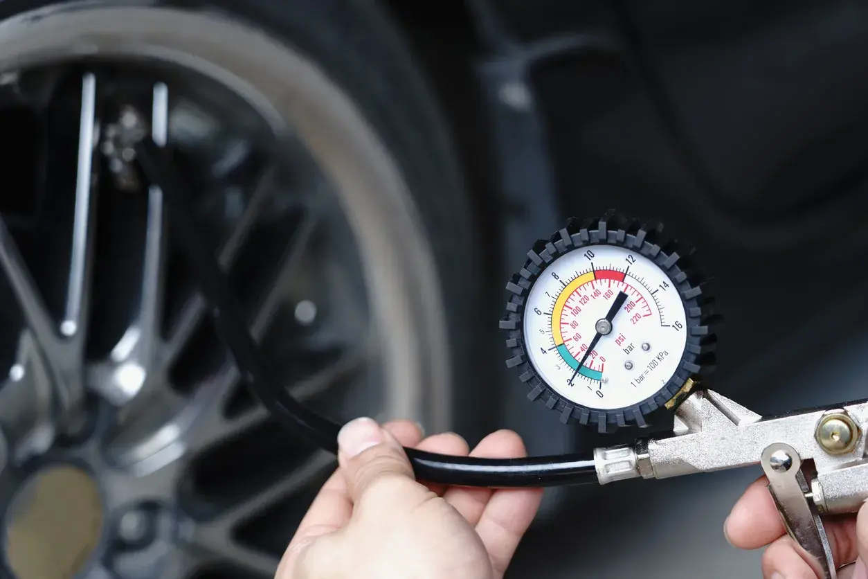 Main tenant vérifie la pression du pneu de voiture avec un manomètre. Il est prêt à gonfler le pneu.