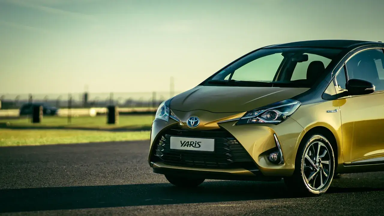 Toyota Yaris hybride dorée sur route asphaltée, prête pour sa vidange.