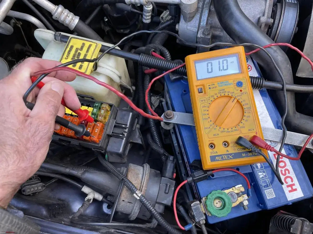 Diagnostic d'une batterie qui se décharge vite : un multimètre mesure le courant sur les fusibles d'une voiture.