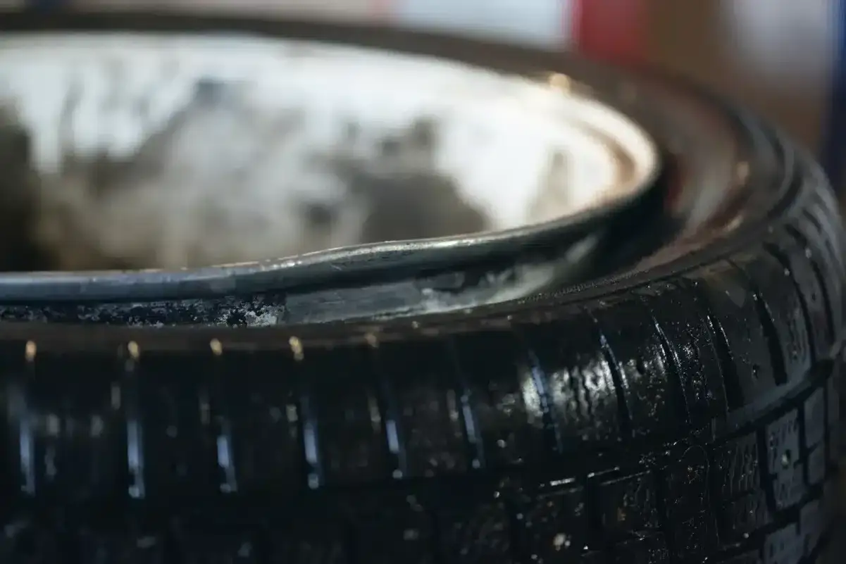 Gros plan sur une roue voilée, le pneu noir brillant et la jante métallique usée.