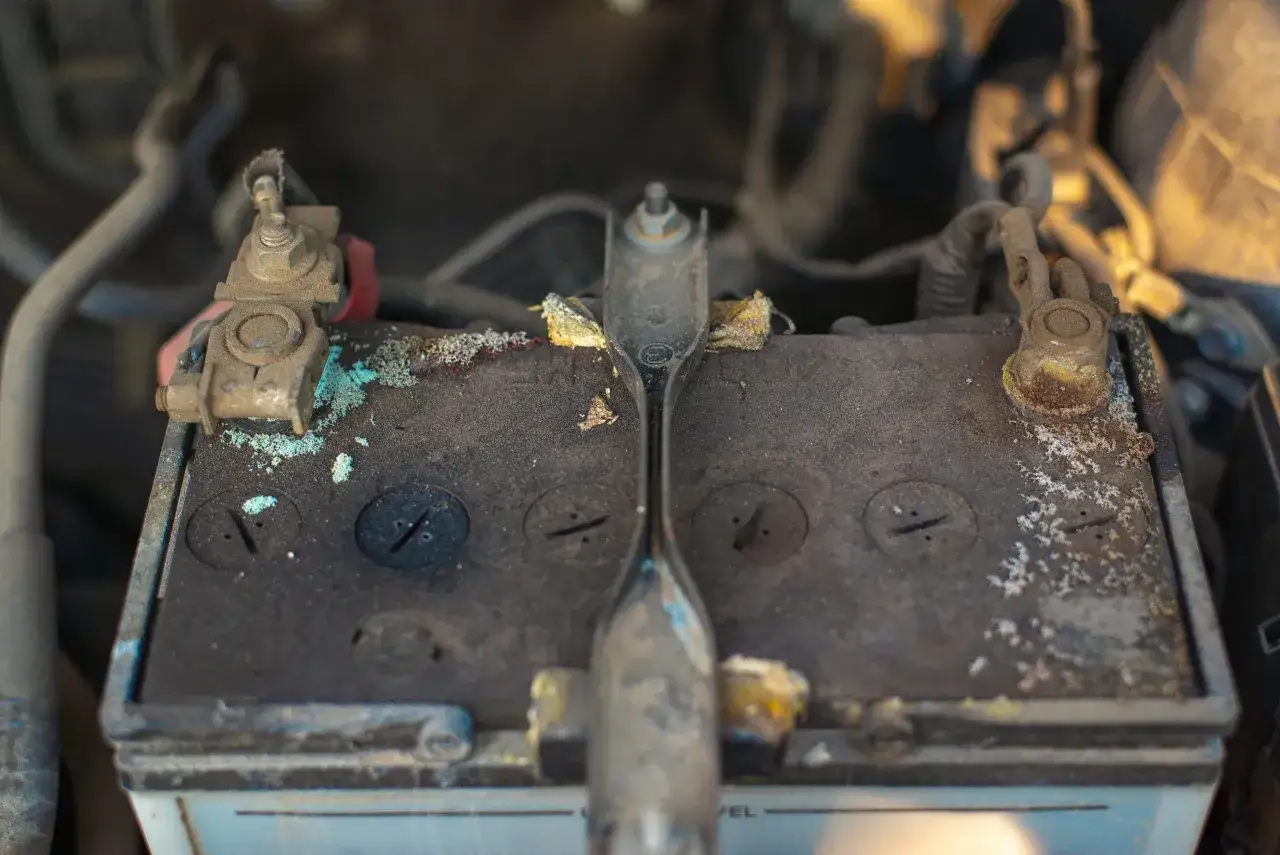 Batterie de voiture corrodée, avec des dépôts verts et blancs. Comment tester une batterie sans multimètre ? Observez les bornes et la surface.