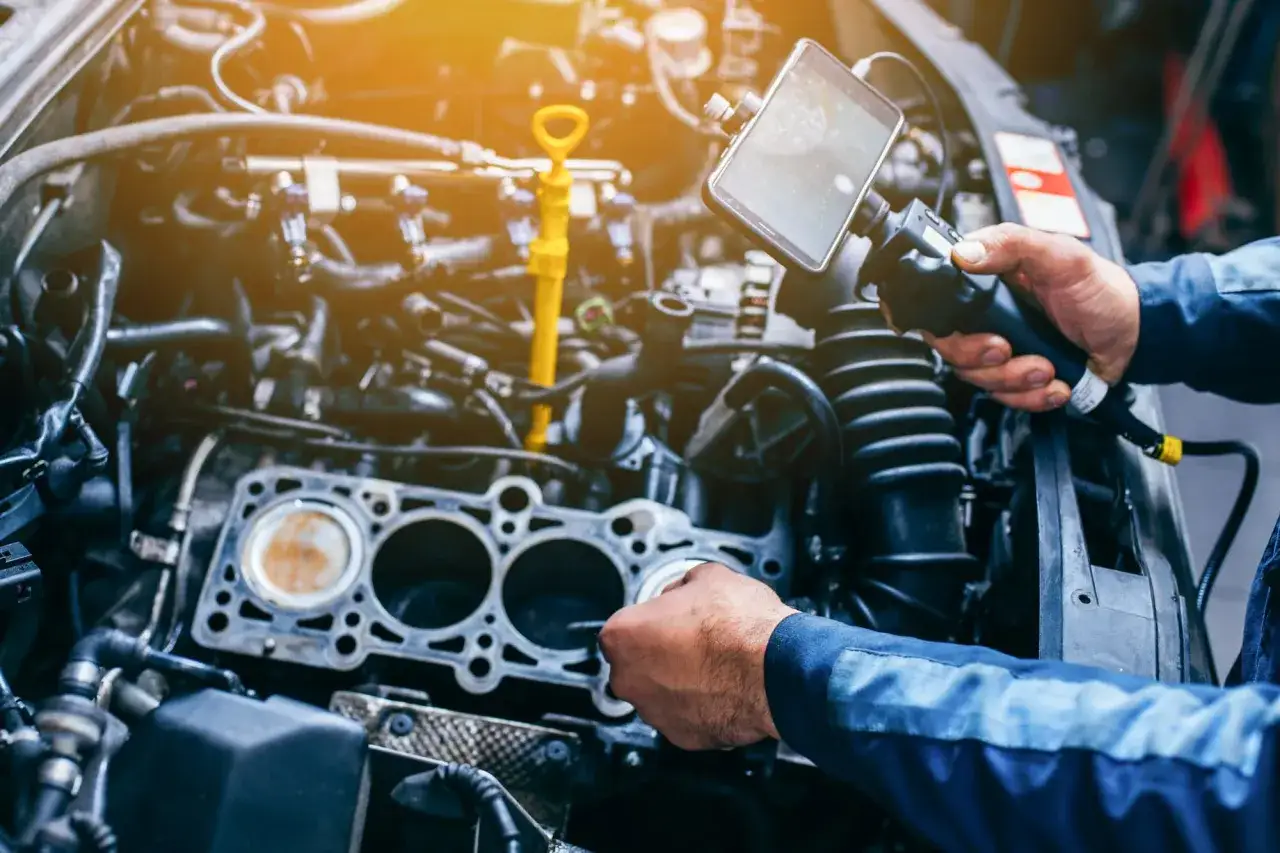 M&eacute;canicien v&eacute;rifiant le moteur pour estimer le changer soupape moteur prix. Diagnostic d'un probl&egrave;me m&eacute;canique complexe.