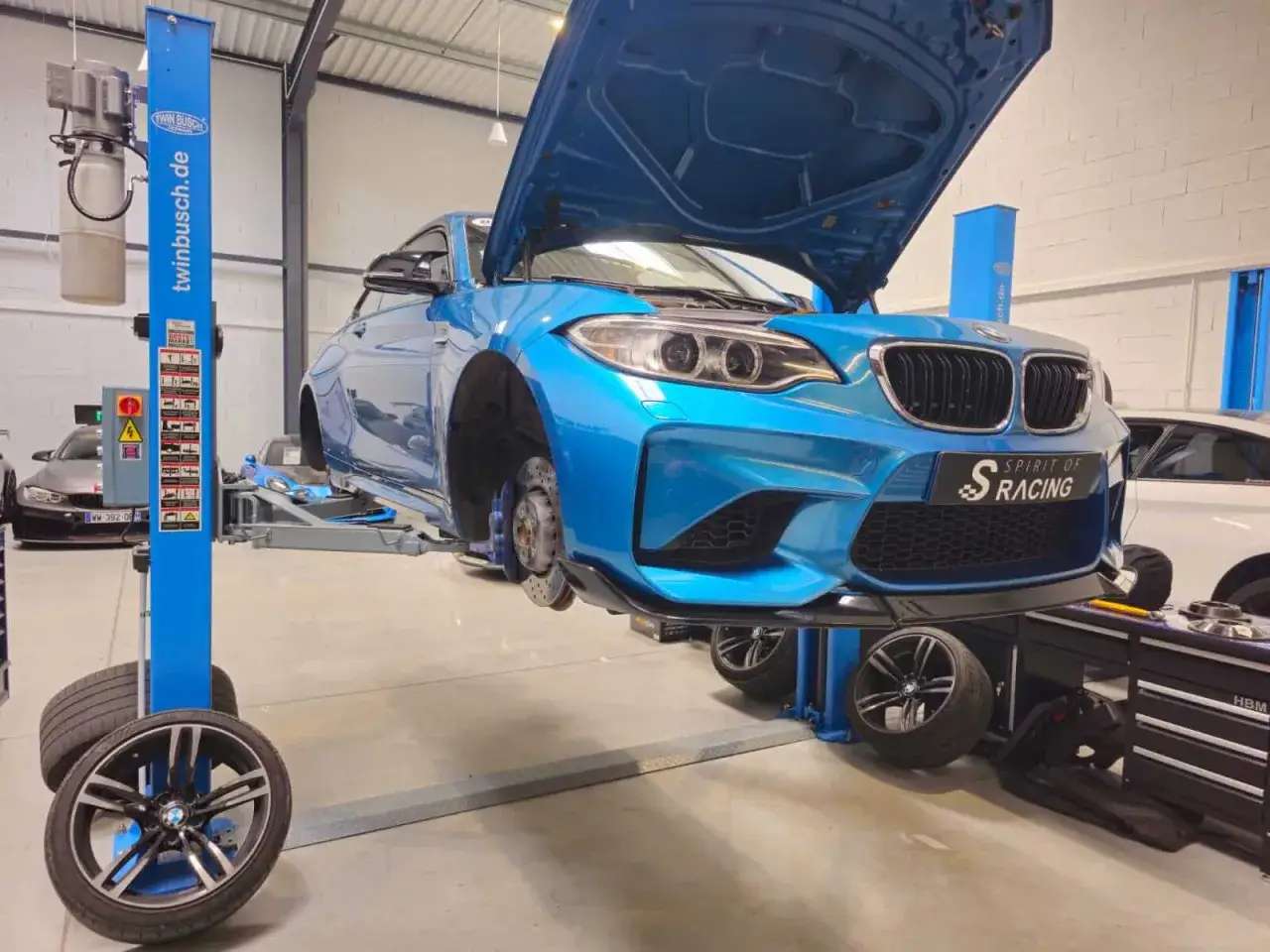 Une BMW bleue sur un pont élévateur, prête pour une vidange. Le prix de la vidange chez BMW est une préoccupation pour de nombreux propriétaires.