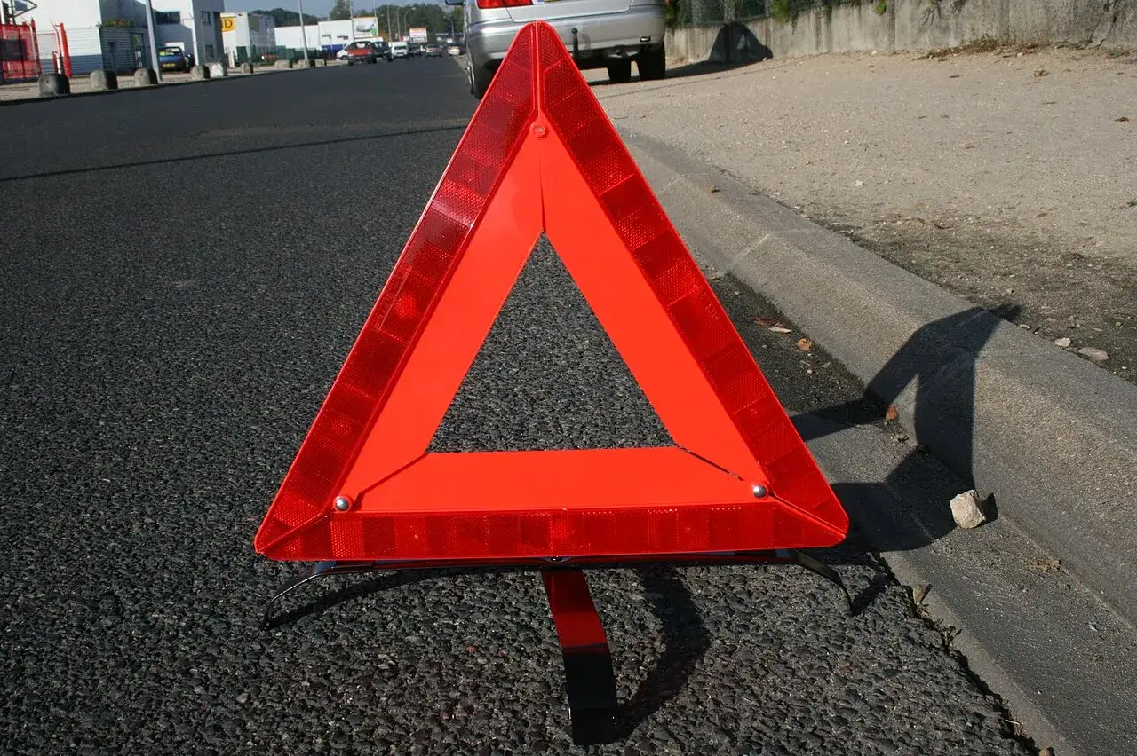 Triangle rouge de signalisation sur la route, indiquant un danger. Ces feux de détresse sont essentiels pour la sécurité routière.