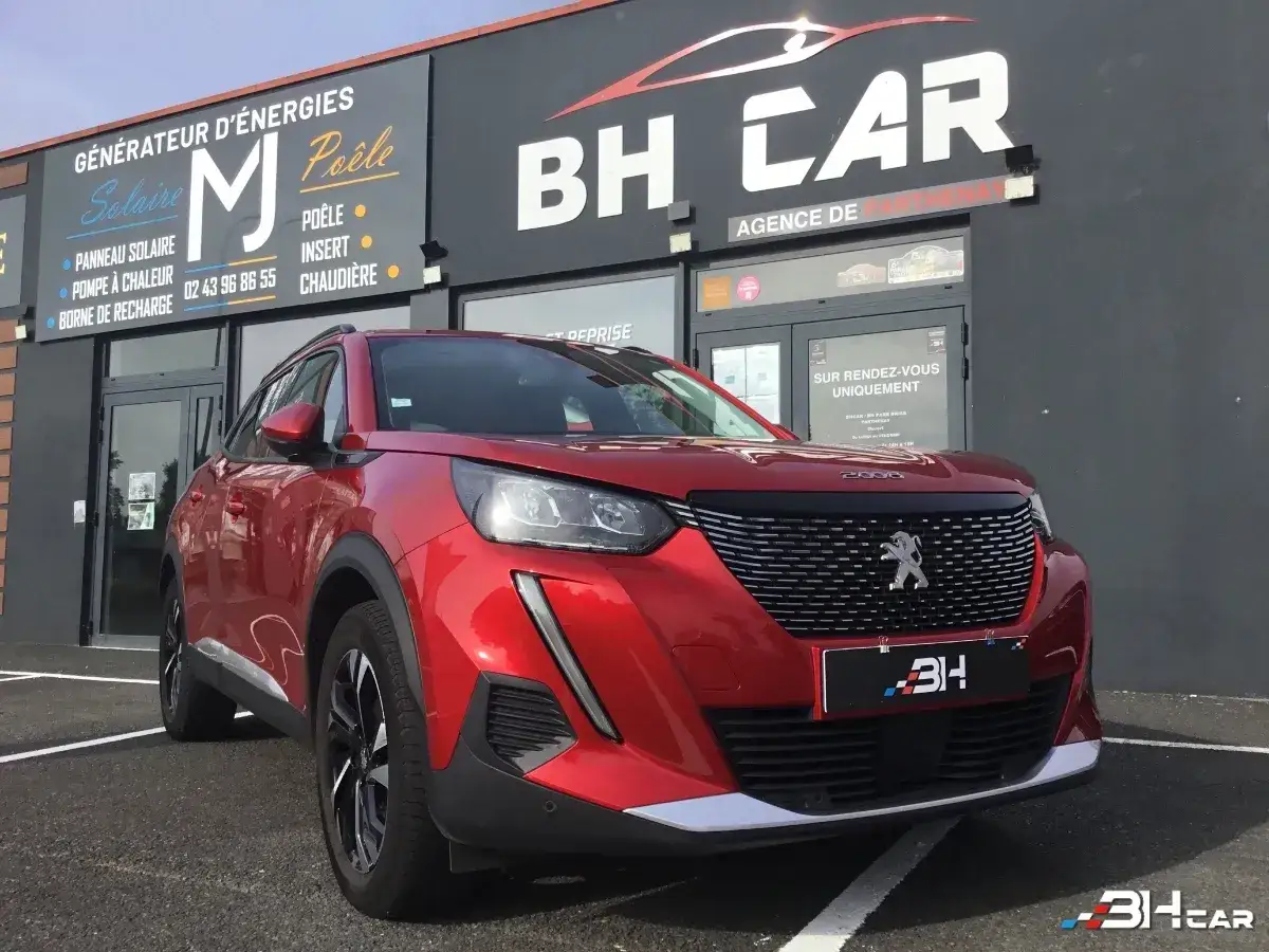Peugeot 2008 rouge devant une agence auto. Demandez le tarif r&eacute;vision Peugeot 2008 chez BH Car.