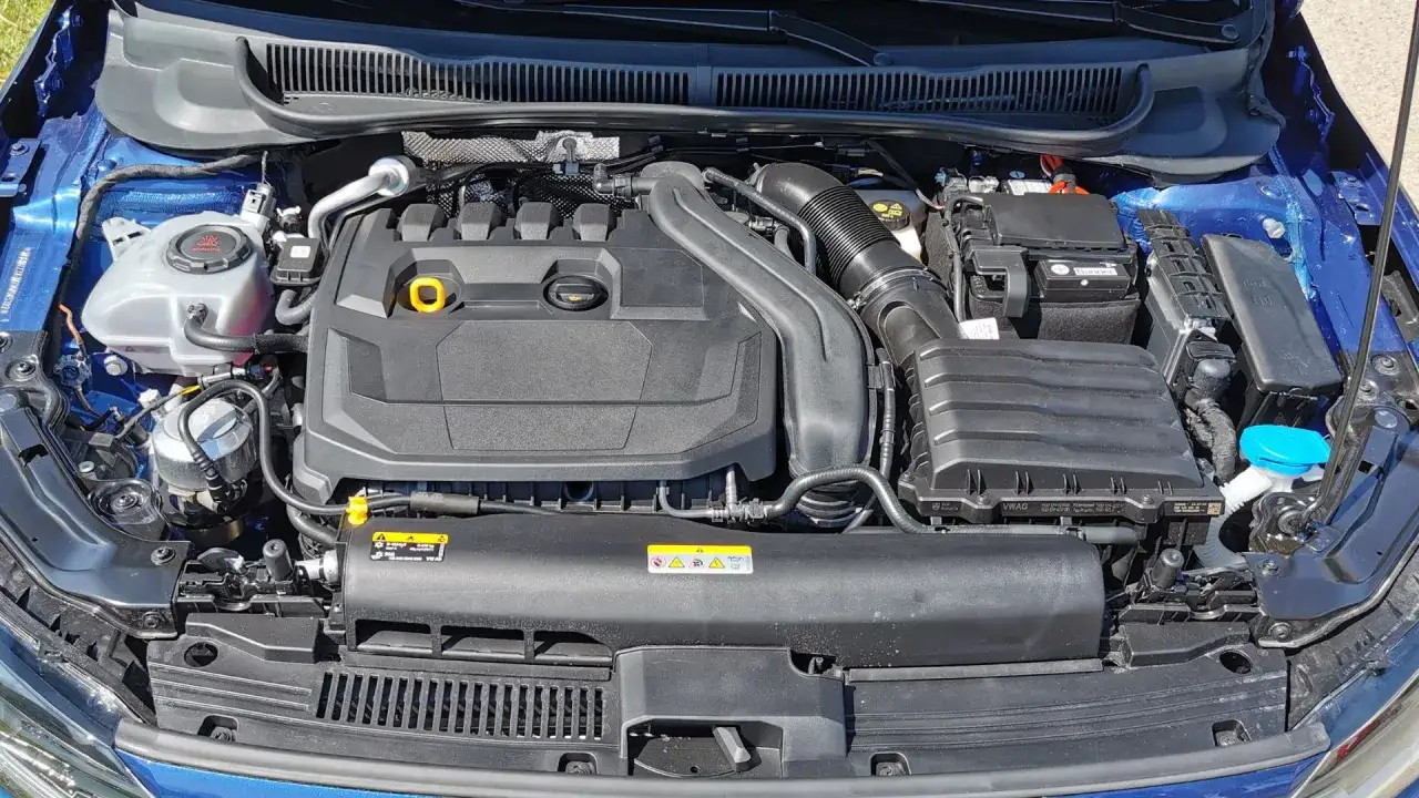 Moteur d'une Polo 6 bleu, prêt pour la vidange. On y voit le réservoir de liquide de refroidissement, le cache moteur noir, la batterie et le système d'admission d'air.