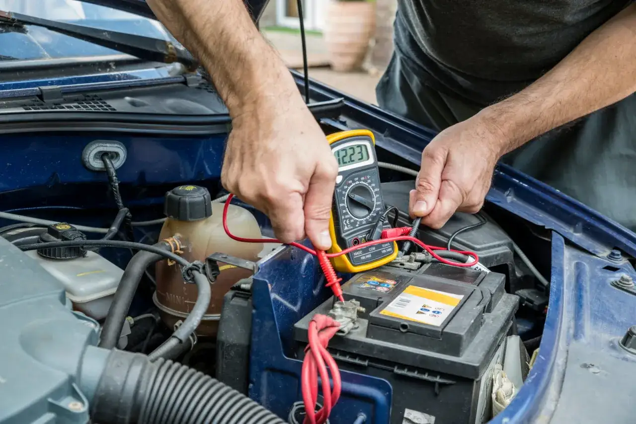 Un mécanicien vérifie la batterie d'une voiture avec un multimètre. Le neiman voiture est en cours de diagnostic.