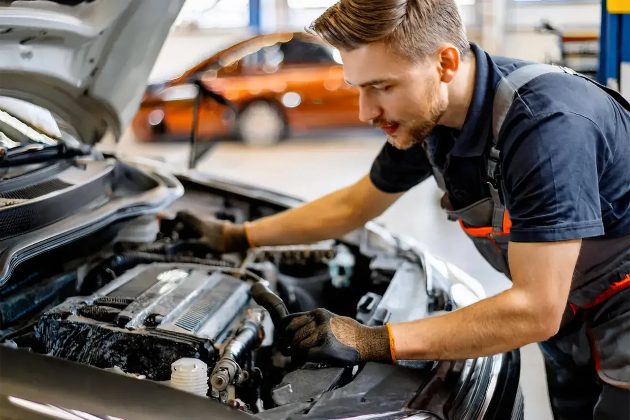 Mécanicien travaillant sur le moteur d'une voiture. Apprenez comment changer une batterie de voiture sans perdre les données.