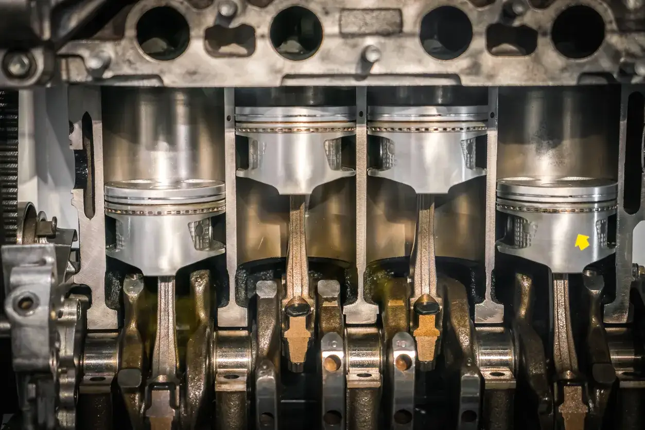 Vue en coupe d'un moteur montrant la segmentation moteur, les pistons, les bielles et le vilebrequin. Une flèche jaune pointe vers un piston.