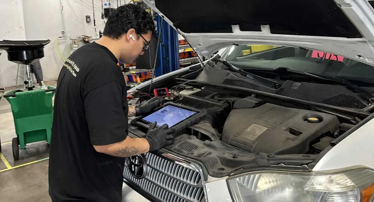 Un mécanicien effectue une révision de voiture électrique, consultant une tablette pour diagnostiquer le moteur.