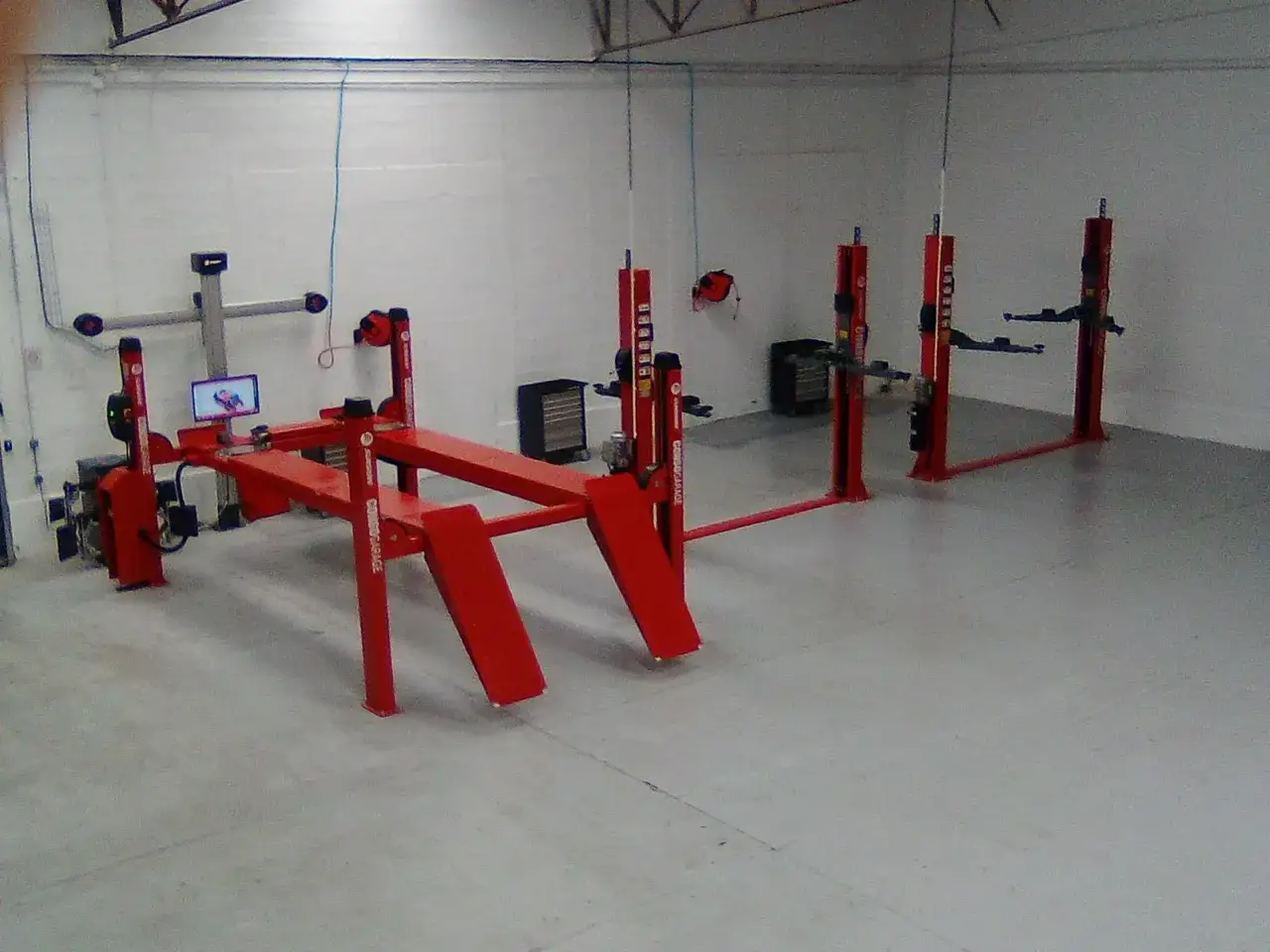 Un garage libre service pour r&eacute;parer soi-m&ecirc;me, avec plusieurs ponts &eacute;l&eacute;vateurs rouges pr&ecirc;ts &agrave; accueillir des v&eacute;hicules.